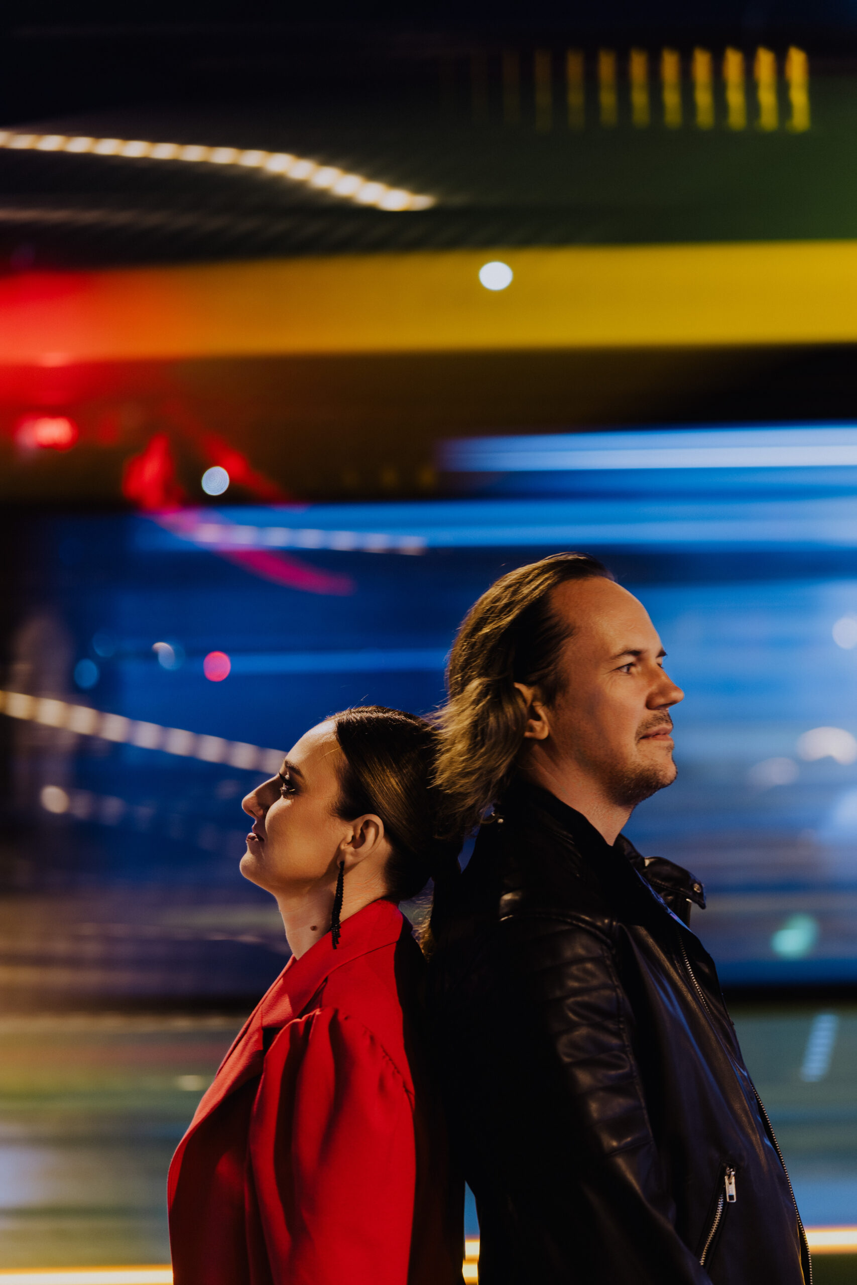 Magdalena i Adrian z Neonów Nocy, stojący plecami do siebie na tle kolorowych świateł